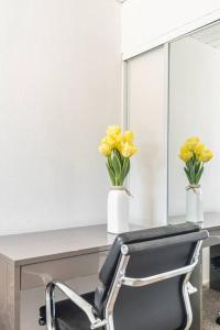 ミルピータスにあるMilpitas Homestay Roomのデスク(椅子付)、黄色い花の花瓶