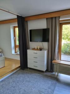 a living room with a tv and a white dresser at Einmal Auftanken bitte... Kiel...direkt am See.. in Molfsee