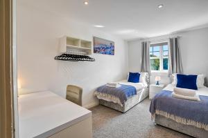 a white bedroom with two beds and a window at Sandy Lane Apartment in Skelmersdale