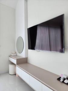 een badkamer met een tv aan een witte muur bij กอลมาร์ พูลวิลล่า เขาใหญ่ in Pong Talong