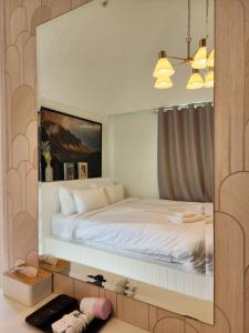 een slaapkamer met een groot wit bed in een spiegel bij กอลมาร์ พูลวิลล่า เขาใหญ่ in Pong Talong