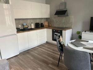 a kitchen with white cabinets and a table with a laptop at La Mia Casa Apartament Świdnica in Świdnica +5 photos