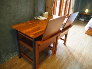 een houten tafel met 2 stoelen en een bureau bij Banmai87 Guest House บ้านไม้87 เกสต์เฮ้าส์ in Phra Nakhon Si Ayutthaya