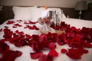 a bunch of red roses on a bed with a wine glass at Pousada Paraíso Tropical in Penha