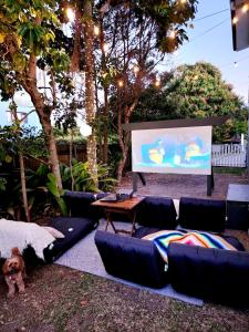 una pantalla grande en un patio con sofás y una mesa en Stunning Beach House & Glamping tent - Sunshine Coast, en Caloundra