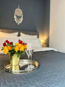 a tray with two glasses and a vase of flowers on a bed at Blue Boho Studio Brasov with Terrasse and Panoramic view in Braşov