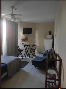 1 dormitorio con 1 cama, mesa y sillas en Tardeli Suite dos anjos com sacada, en Arraial do Cabo