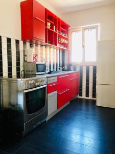 cocina con armarios rojos y horno de acero inoxidable en Apartman STUDIO Sch Sch Sch, en Sarajevo