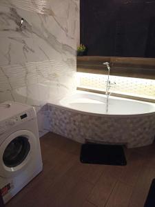 a bath tub in a bathroom with a washing machine at Markowia in Marki +9 photos