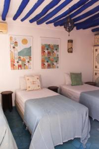 2 Betten in einem Zimmer mit blauen Decken in der Unterkunft Riad Dar Nael in Marrakesch