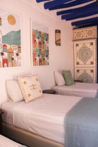 2 camas en una habitación con paredes blancas y techos azules en Riad Dar Nael, en Marrakech