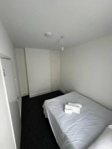 a white room with a bed with two towels on it at Spacious 5-Bedroom Urban Haven in Luton