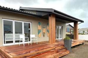 a house with a wooden deck with surfboards on it at Happy Dayz Holiday House in Jeffreys Bay