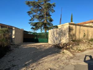 a fence and a tree next to a wall at Jolie maison individuelle 45m2 in Saint-Mitre-les-Remparts