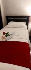Una cama roja y blanca con un sombrero. en Tamrah Suites Hotel, en Amán