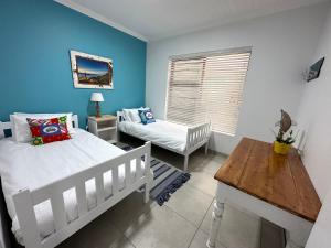 a bedroom with two beds and a table and a window at Happy Dayz Holiday House in Jeffreys Bay