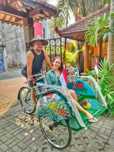 un hombre y una mujer sentados en una bicicleta en Bedhot Homestay en Yogyakarta