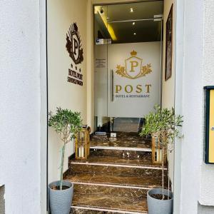 Hotel Post Sindelfingen في شيندلفينجن: باب لمكتب بريد مع اثنين من النباتات الفخارية