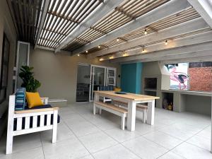 a patio with a wooden table and a bench at Happy Dayz Holiday House in Jeffreys Bay