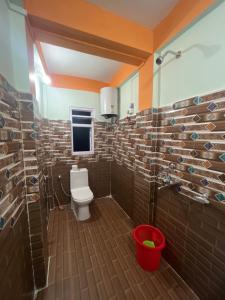 La salle de bains est pourvue de toilettes et d'un mur en briques. dans l'établissement Taktserholidays, à Tawang