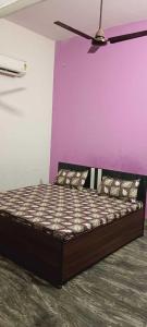 Cama en habitación con pared púrpura en SPOT ON Hotel Golden Gajraula, en Gajraula