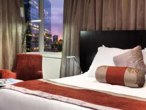 a bed in a hotel room with a large window at Hotel Grand Chancellor Melbourne in Melbourne