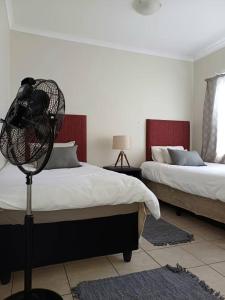 1 dormitorio con 2 camas y ventilador en el suelo en ABSOLUTE AIRBNB en Windhoek