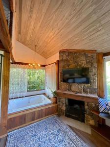 baño grande con bañera grande y TV en Cabana Mirim Estalagem Rural, en Gramado