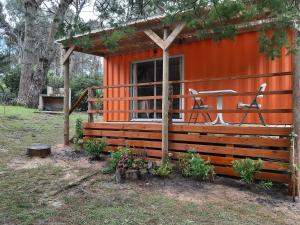 Cabaña pequeña de color naranja con porche y 2 sillas en Helles, modernes Containerhaus, en Punta del Este