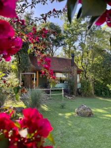 uma casa com um quintal com flores em frente em Cabana Mirim Estalagem Rural em Gramado