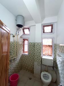 y baño con aseo, lavabo y ventanas. en Ajanta Lodge, en Guwahati