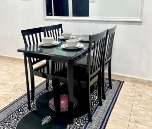 un tavolo nero con sedie e ciotole e piatti di Sukay Homestay a Kuala Terengganu