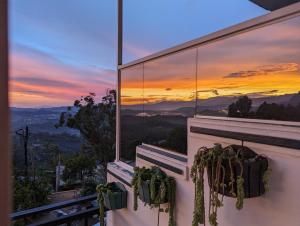 een uitzicht op de zonsondergang vanaf een balkon met planten bij Nilowin Glenanore Guesthouse in Haputale