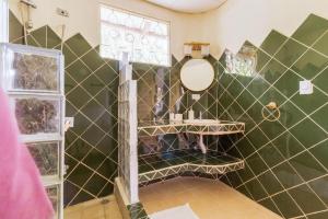 baño con paredes de azulejos verdes y espejo en Casa Mazam en Talamanca