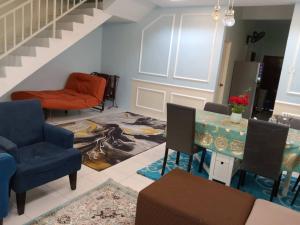 a living room with chairs and a table and stairs at Syed Homestay Arau in Arau