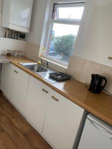 eine Küche mit weißen Schränken, einem Waschbecken und einem Fenster in der Unterkunft New 2 bedroom Apartment in Greater Manchester in Ashton under Lyne