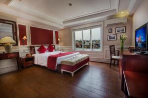 Dormitorio con cama, escritorio y TV en La Beaute De Hanoi Hotel, en Hanói