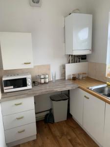 eine kleine Küche mit weißen Schränken und einer Mikrowelle in der Unterkunft New 2 bedroom Apartment in Greater Manchester in Ashton under Lyne