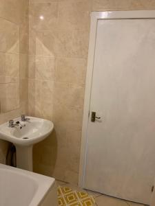ein Badezimmer mit einem Waschbecken und einer weißen Duschtür in der Unterkunft New 2 bedroom Apartment in Greater Manchester in Ashton under Lyne