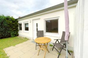 a patio with a table and chairs and a house at An den Kreischen 28 Ferienbungalow Engel in Ueckeritz