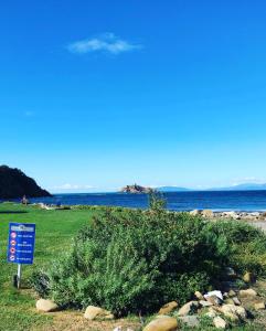una señal azul junto a un arbusto junto al océano en Confortevole Bilocale Giardino Doppio Parcheggio, en Punta Ala