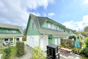 a green and white house with a yard at Ferienhaus Anja 3 in Ueckeritz
