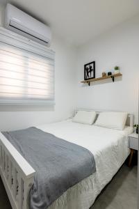 a white bedroom with a bed and a window at Luxury Central Old Town Apartment in Beer Sheva