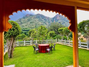 Udai Valley Resort- Top Rated Resort in Udaipur with mountain view في أودايبور: طاولة وكراسي في ساحة مع جبل