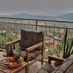 una silla en un balcón con un bol de frutas y copas de vino en Gardenia en ‘Ein el Asad
