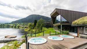 a house with three hot tubs on a deck next to a river at Elva Hotel in Skulestadmo