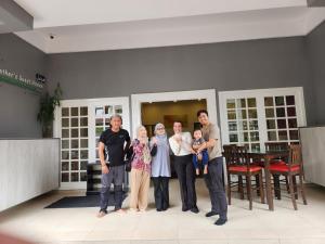 een gezin dat poseert voor een foto in een woonkamer bij Fathers Guesthouse in Tanah Rata