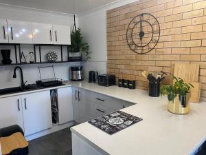 a kitchen with white cabinets and a brick wall at Beach House in Yeppoon