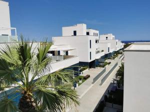 ein weißes Gebäude mit einer Palme davor in der Unterkunft Turquesa Del Mar - Max Beach Golf - Ground Floor Apartment in Playa Flamenca