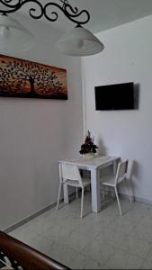 a white dining room table with two chairs and a television at La Foggia seaside paradise in Siculiana